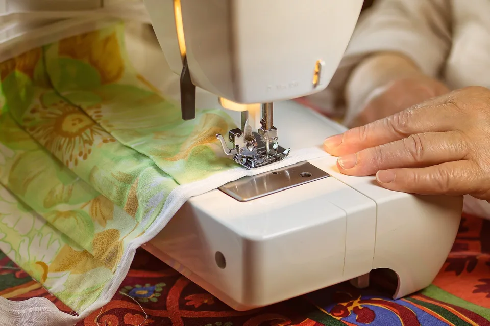 Hands guiding fabric through a sewing machine.