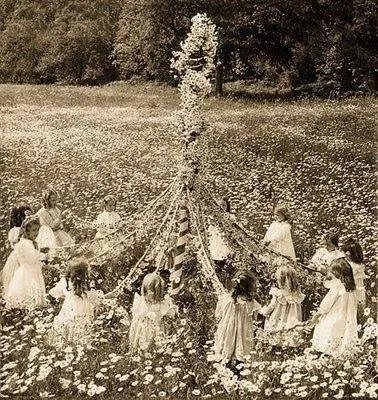 An old photograph of people dancing around a maypole.