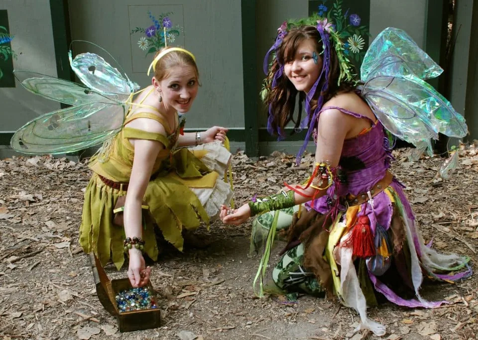 Two children dressed as fairies beside a woodland path.