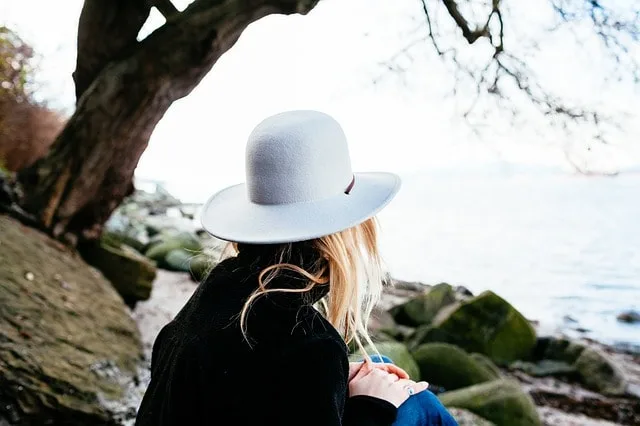A woman wearing a sun hat by the water.