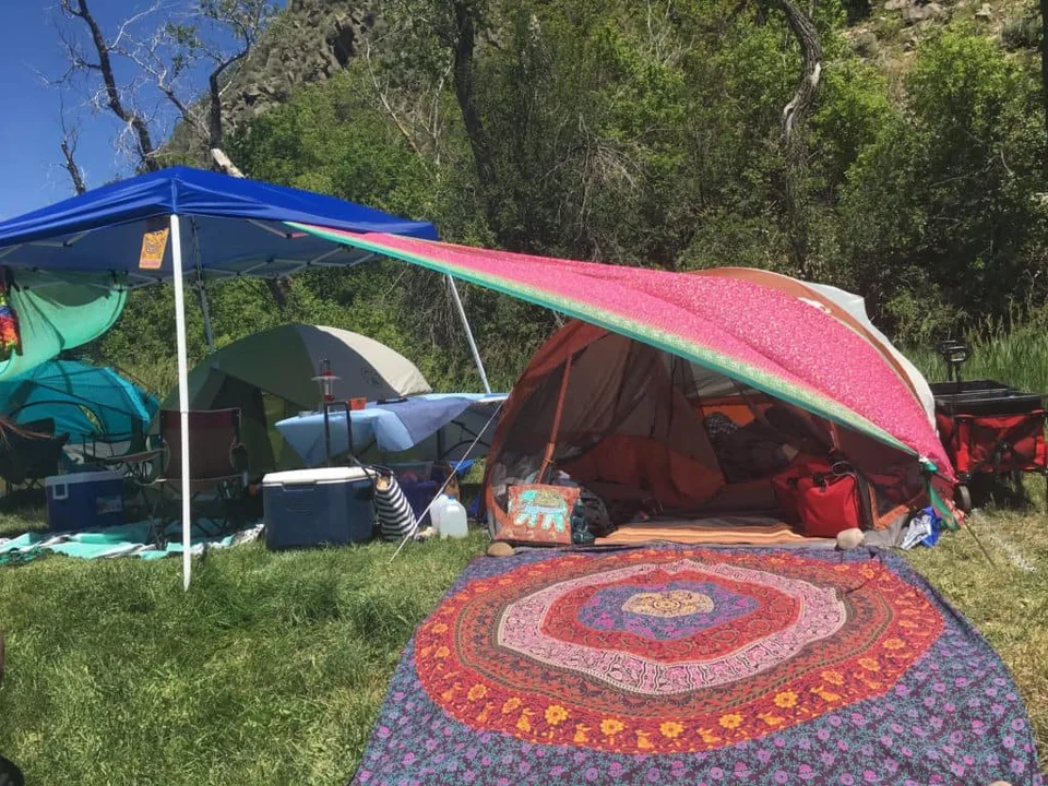 Colorful tents and shaded seating at a campsite.