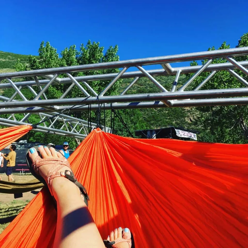 A person's feet in a bright hammock beneath a metal frame.