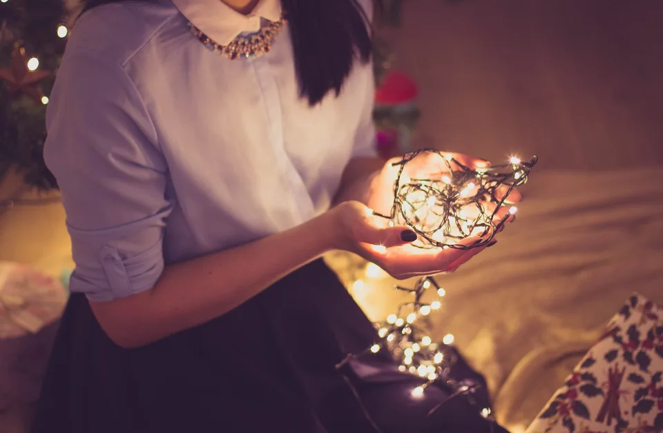 A woman holding a bundle of glowing string lights.