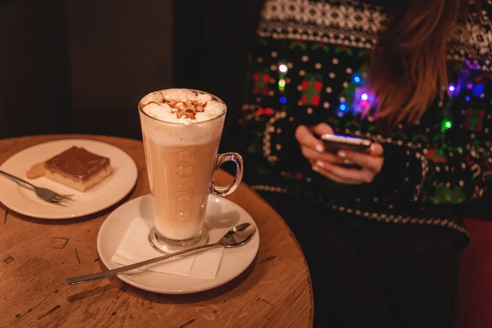 A hot drink and a decorated Christmas sweater.