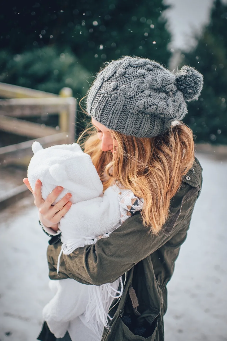 An adult holding a baby outdoors in winter.