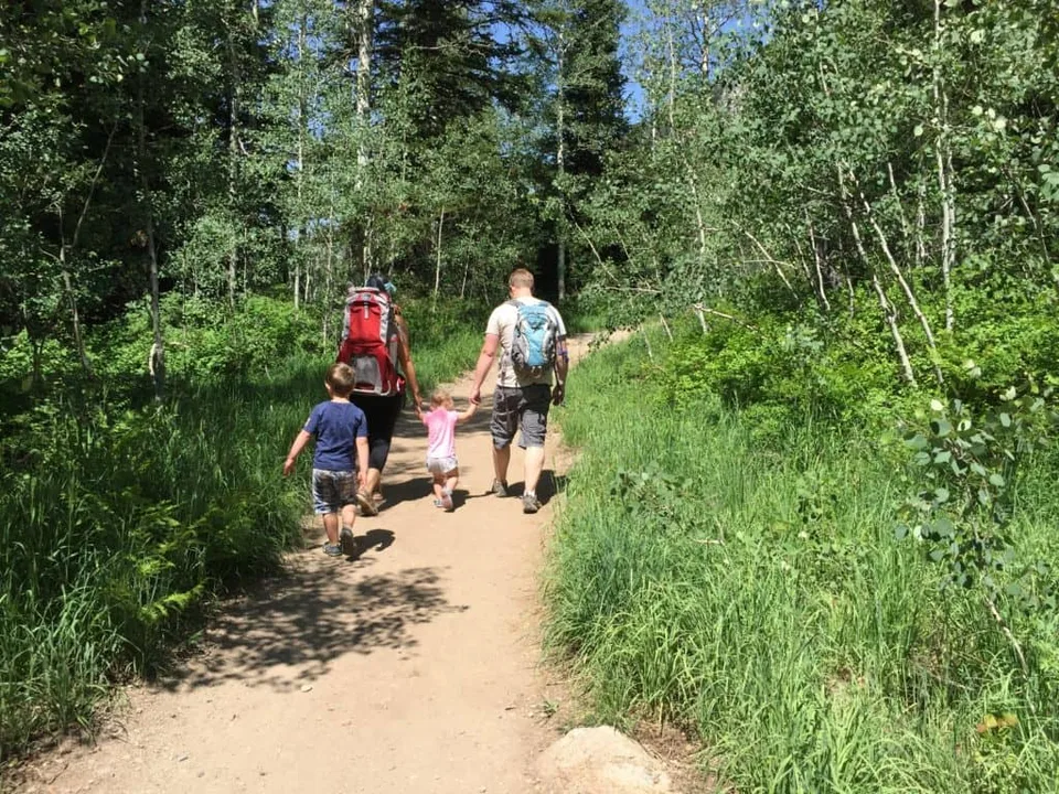 An adult and children walking along a wooded trail.
