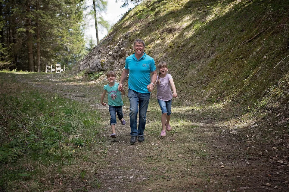 An adult and children walking along a woodland path.