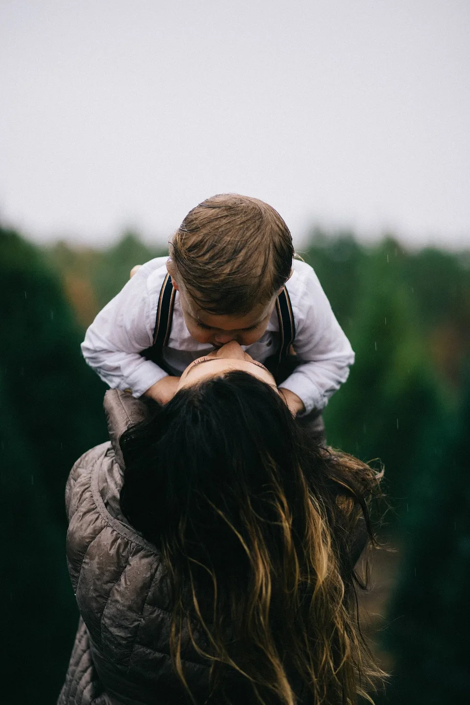 A child riding on an adult's shoulders in a field.