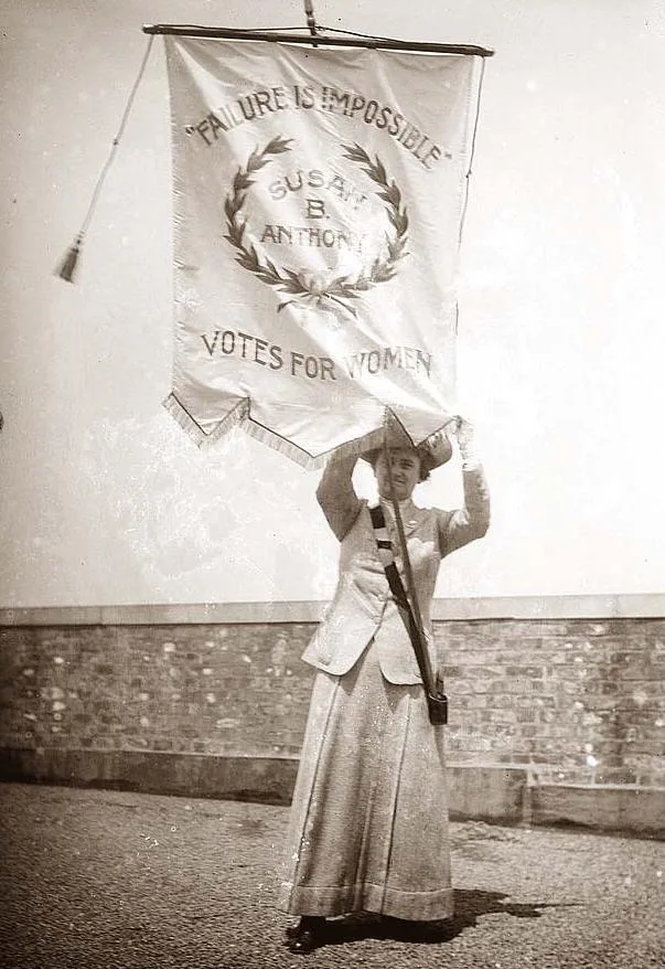 An old photograph of a woman holding a large wreath overhead.