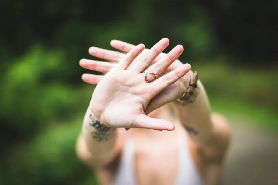 A woman holding her hands in front of her face outdoors.